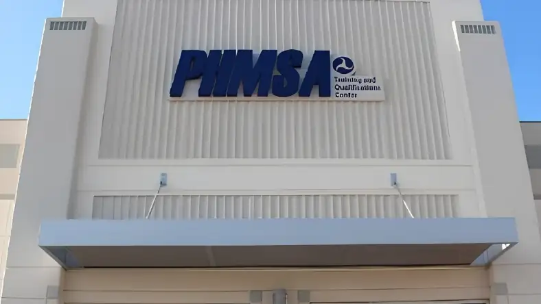 An exterior building sign reads PHMSA Training and Qualifications Center above a covered walkway entrance